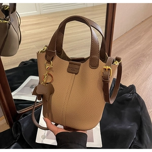 Detail of two-tone bucket bag with leather elephant charm and mirror reflection effect