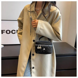 Détail du sac vanité matelassé noir avec chaîne argentée et boucle à bille en métal réglable