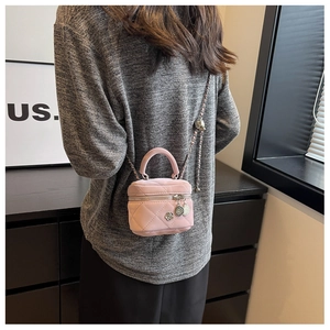 Détail du sac à bandoulière rose matelassé avec chaîne en métal et breloque camélia