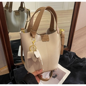 Detailed macro view of cream litchi grain leather bucket bag with brown contrast handle