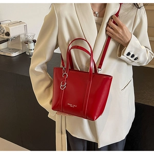 Detail of red glossy leather tote bag with MOKANI YOLE PARIS logo and adjustable strap