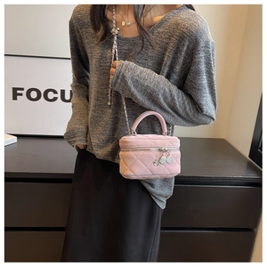 Détail du mini sac seau en cuir matelassé rose avec bandoulière chaîne et breloque fleur