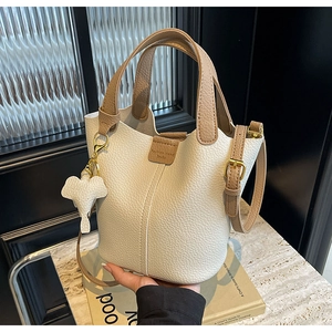 Detail of creamy bucket bag with lychee texture leather and a cute elephant charm