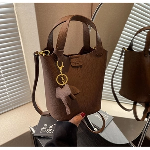 Detail view of brown leather bucket bag featuring elephant charm and magnetic closure