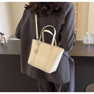 Detail of cream leather tote bag with metal ring hardware and detachable shoulder strap