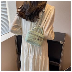 Détail du mini sac matelassé vert menthe avec bandoulière chaîne et breloques à fleurs