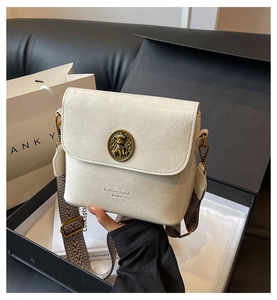 Détail du fermoir ours en métal rétro sur un sac seau en cuir crème texturé élégant