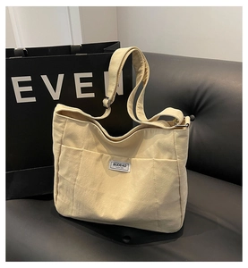 Close-up of beige canvas tote bag with multiple pockets and adjustable shoulder strap