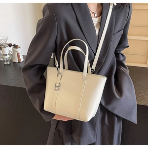 Detail of a beige leather tote bag with vertical stitching and adjustable shoulder strap