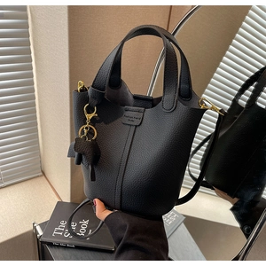 Detail of black lychee grain bucket bag with dual handles and elephant pendant charm