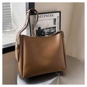 Detail of warm brown leather bucket bag with metal buckle strap on a round metal table