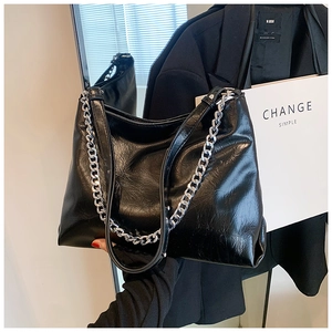 Close-up of black wrinkled leather tote with chunky silver chain detail for work