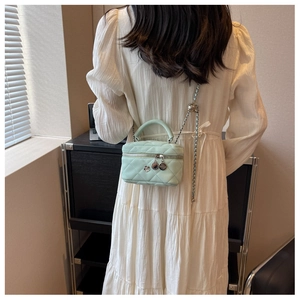 Mini sac seau matelassé vert menthe porté par un mannequin en robe plissée