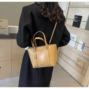 Model wearing a mustard yellow tote bag over a black blazer in a library setting
