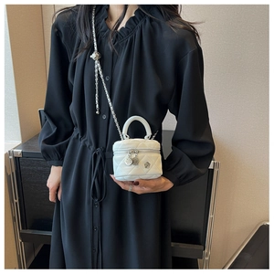 Gros plan du mini sac matelassé blanc avec fermeture camélia et bandoulière chaîne