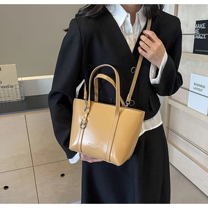 Detail of light brown PU leather tote bag showing crossbody strap and model commute style