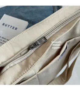 Close-up of smooth metal zipper and rectangular puller on a beige canvas tote bag