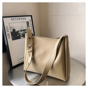 Detail view of beige leather tote bag with silver cylindrical metal buckle and wide strap