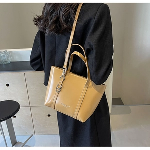 Detail of mustard yellow tote bag with metal chain and adjustable crossbody strap