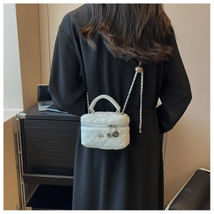 Détail du mini sac boîte matelassé blanc avec chaîne argentée et breloque fleur