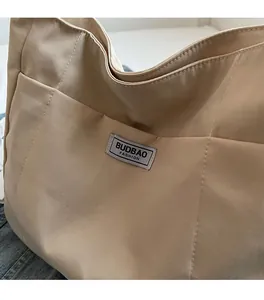 Detailed macro view of beige canvas tote bag material and woven BUDBAO logo patch