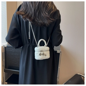 Vue arrière du mannequin portant un sac seau matelassé blanc avec breloque florale