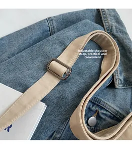 Detail of blue denim canvas tote bag showing adjustable beige strap and metal buckle