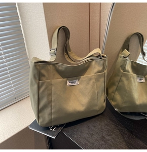 Detail of adjustable metal buckle and brand label on large green canvas tote bag