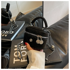 Détail du mini sac seau en velours matelassé noir avec breloque fleurie et bandoulière