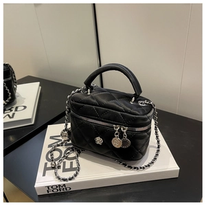 Détail du mini sac seau en cuir matelassé noir avec bandoulière et breloque fleur