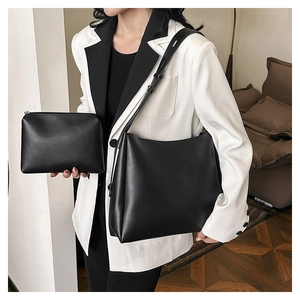 Detail of minimalist black leather tote and matching zipper pouch set with wide strap