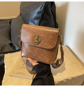 Détail du sac seau marron vintage avec emblème métallique et large bandoulière à motifs