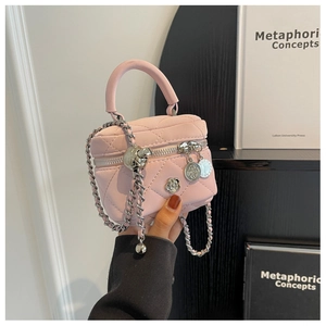 Gros plan du mini sac seau matelassé rose avec chaîne argentée et breloque fleurie