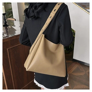 Rear view of khaki leather tote bag with wide adjustable shoulder strap on model
