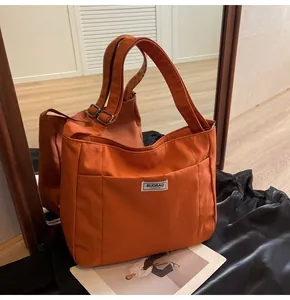 Detail of vibrant orange canvas tote bag with adjustable strap and fashion label tag