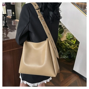 Detail of adjustable wide shoulder strap on khaki leather bucket bag with metal buckle