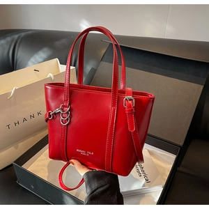 Close-up of bright red tote bag in luxury gift box with chain strap and branding