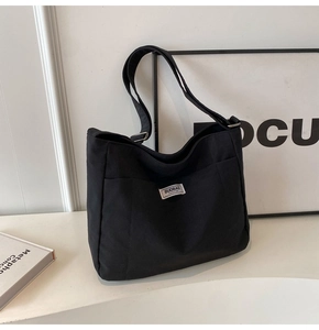 Detail of adjustable strap and silver metal buckle on a black canvas tote bag