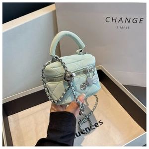 Détail du mini sac matelassé vert menthe avec chaîne argentée et breloques camélia
