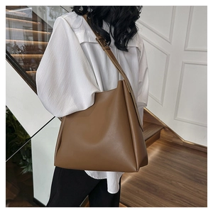 Detailed view of dark brown leather bucket bag worn as a shoulder bag on a model