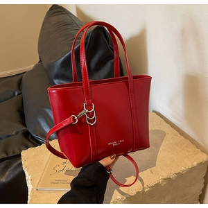 Detail view of red leather tote bag showing silver metal hooks and white brand logo text