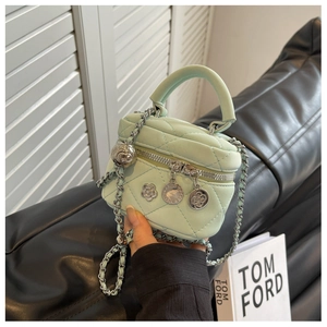 Détail macro du mini sac matelassé vert menthe avec chaîne argentée et breloques chic