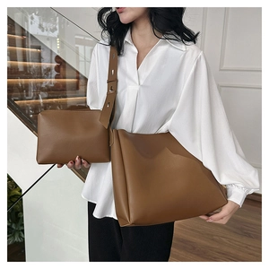 Brown leather tote and small pouch set shown with a model on stairs for size reference