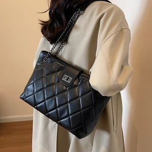 Borsa tote trapuntata in pelle nera con tracolla a catena e chiusura in metallo su modella