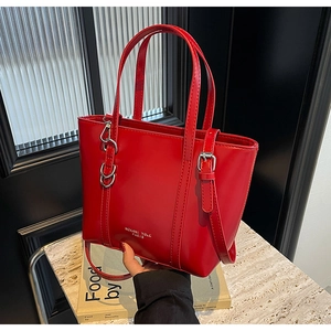 Detail of red leather tote bag with silver metal buckles and adjustable shoulder strap