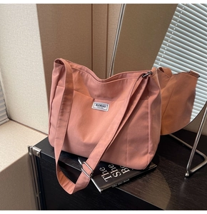 Detailed close-up of pink canvas tote bag showing the fashion label and adjustable strap