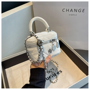 Gros plan du mini sac seau matelassé blanc avec pendentif camélia et bandoulière chaîne