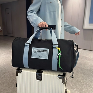Large capacity black oxford travel bag with light blue straps on a white suitcase