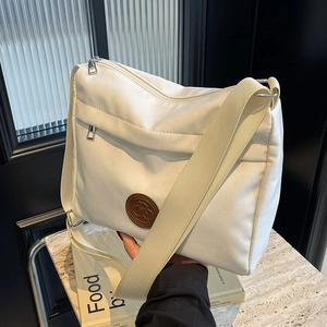 Minimalist beige nylon tote bag with wide shoulder strap and leather logo detail