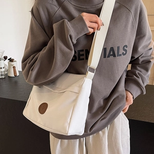 White nylon tote bag with brown logo patch and adjustable wide strap for daily commute